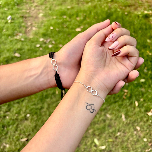 Matching couple infinity bracelets shown on wrists over green grass background