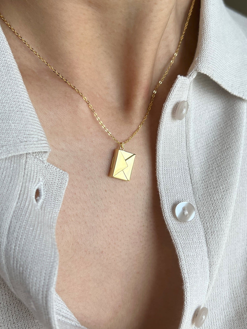 Model wearing gold polished envelope pendant with hidden love message. 