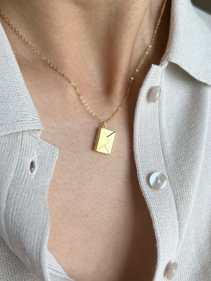 Model wearing gold polished envelope pendant with hidden love message. 