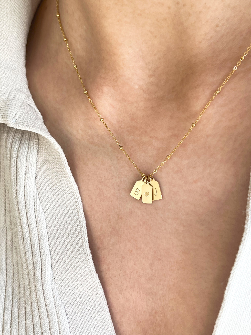 Couple wearing matching gold initial pendants, lifestyle image